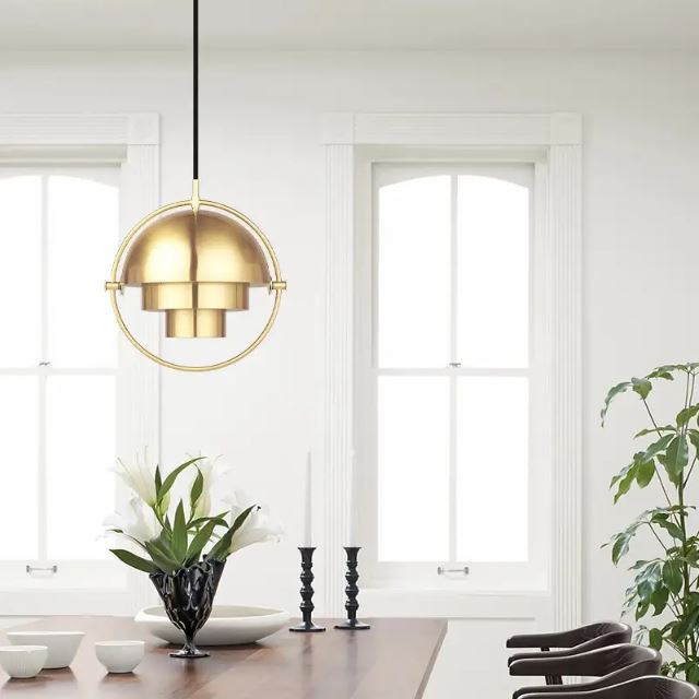 Suspension Gubi Multi Lite dorée suspendue au-dessus d'une table, offrant une ambiance lumineuse et élégante pour une salle à manger.