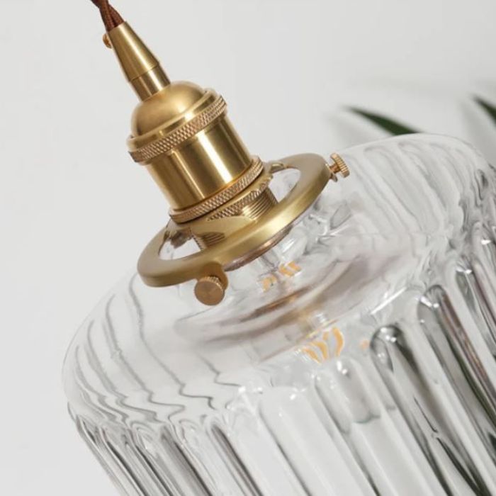 Détail de la suspension holophane montrant la douille en laiton et l’abat-jour en verre strié, alliance de charme et d’élégance.