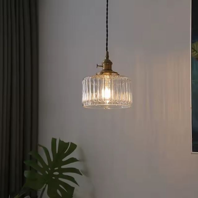 Suspension holophane en verre et laiton allumée dans un salon, créant une ambiance douce et chaleureuse avec un charme rétro.
