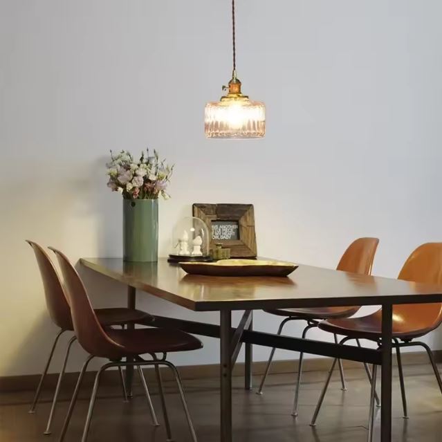 Suspension holophane en verre et laiton au-dessus d’une table de salle à manger, idéale pour une déco vintage chaleureuse.