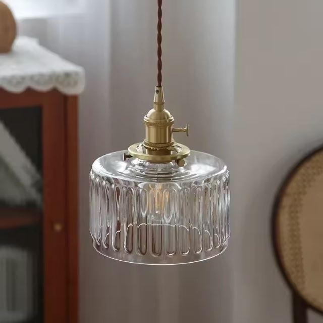 Suspension holophane en verre et laiton dans un intérieur rétro chic, parfaite pour une ambiance douce et lumineuse en coin lecture.