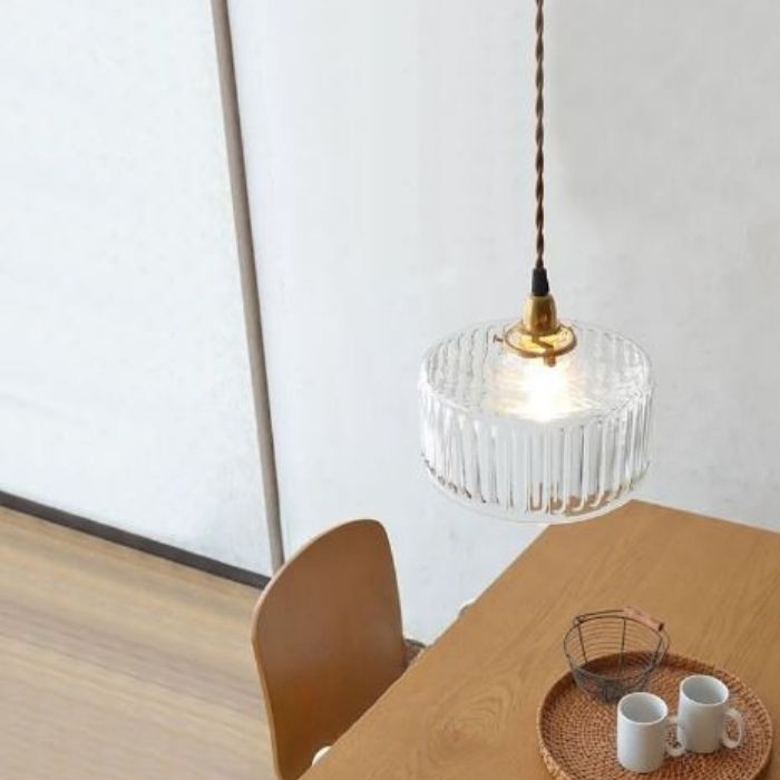 Suspension holophane en verre rayé suspendue au-dessus d’une table, parfaite pour un coin repas au style vintage raffiné.