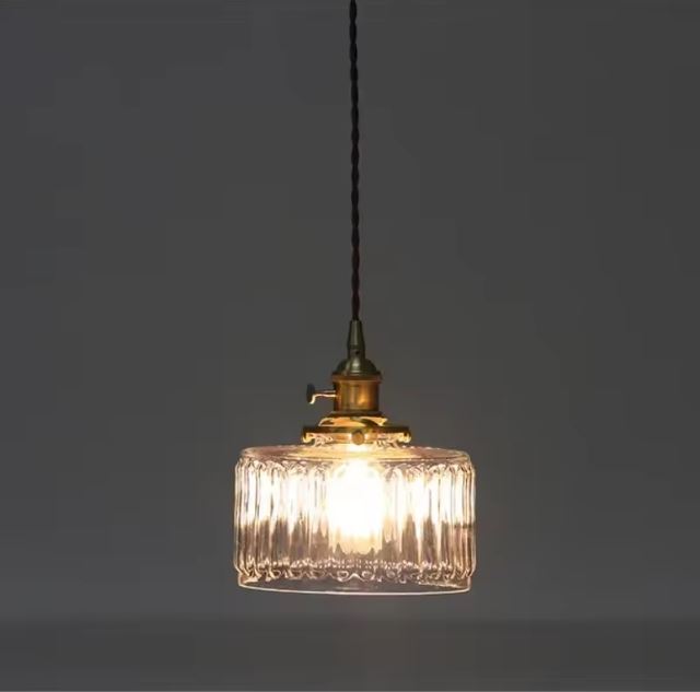 Suspension holophane en verre strié avec ampoule à filament, idéale pour une atmosphère rétro industrielle dans un salon.