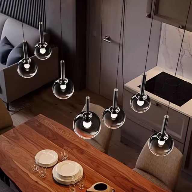 Suspensions à globes en verre fumé noir au-dessus d’une table, esprit moderne chic et chaleureux.