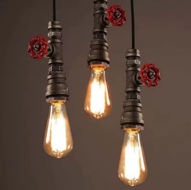 Suspension industrielle tuyau avec trois ampoules Edison et robinets rouges, parfaite pour un éclairage rétro et tendance.