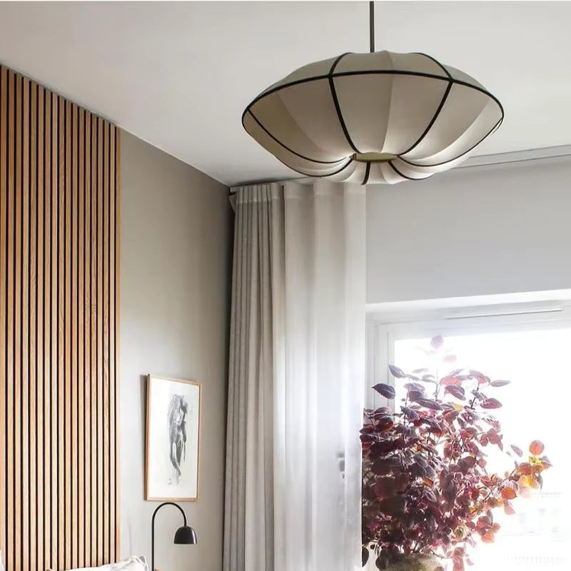 Vue en contre-plongée d'une suspension japonaise aux pétales blancs bordés de noir, dans un intérieur scandinave épuré.