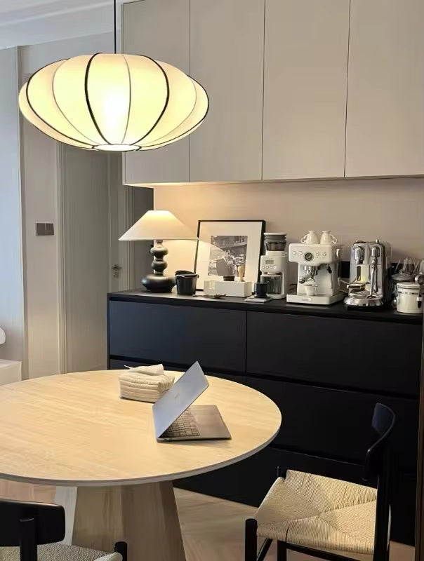 Lanterne japonaise suspendue aux courbes généreuses et nervures noires, illuminant une salle à manger au style Japandi épuré.