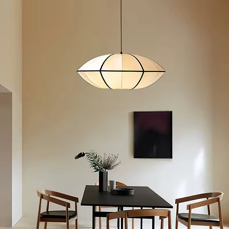 Éclairant une table noire, cette suspension japonaise aux courbes elliptiques et lignes graphiques sublime un décor Japandi.