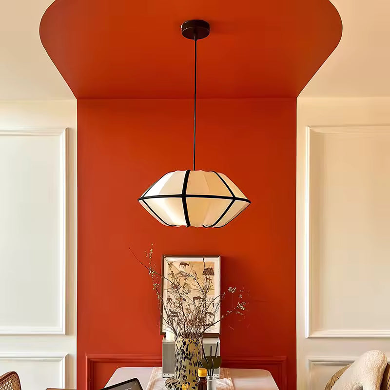 Dans une salle à manger terracotta, suspension japonaise aux formes galbées et lignes noires, d'inspiration Japandi rétro.
