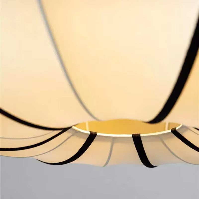 Gros plan sur l'abat-jour d'une suspension japonaise aux plis délicats et lignes noires, éclairé d'une lumière douce.