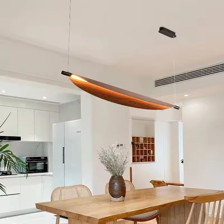 Au-dessus de la table, ce luminaire en lame courbe effet bois affirme un style contemporain, épuré et sculptural