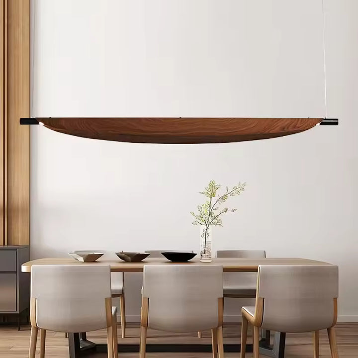 Au-dessus d’une table élégante, la suspension en lame courbe effet bois affirme un style minimaliste et haut de gamme