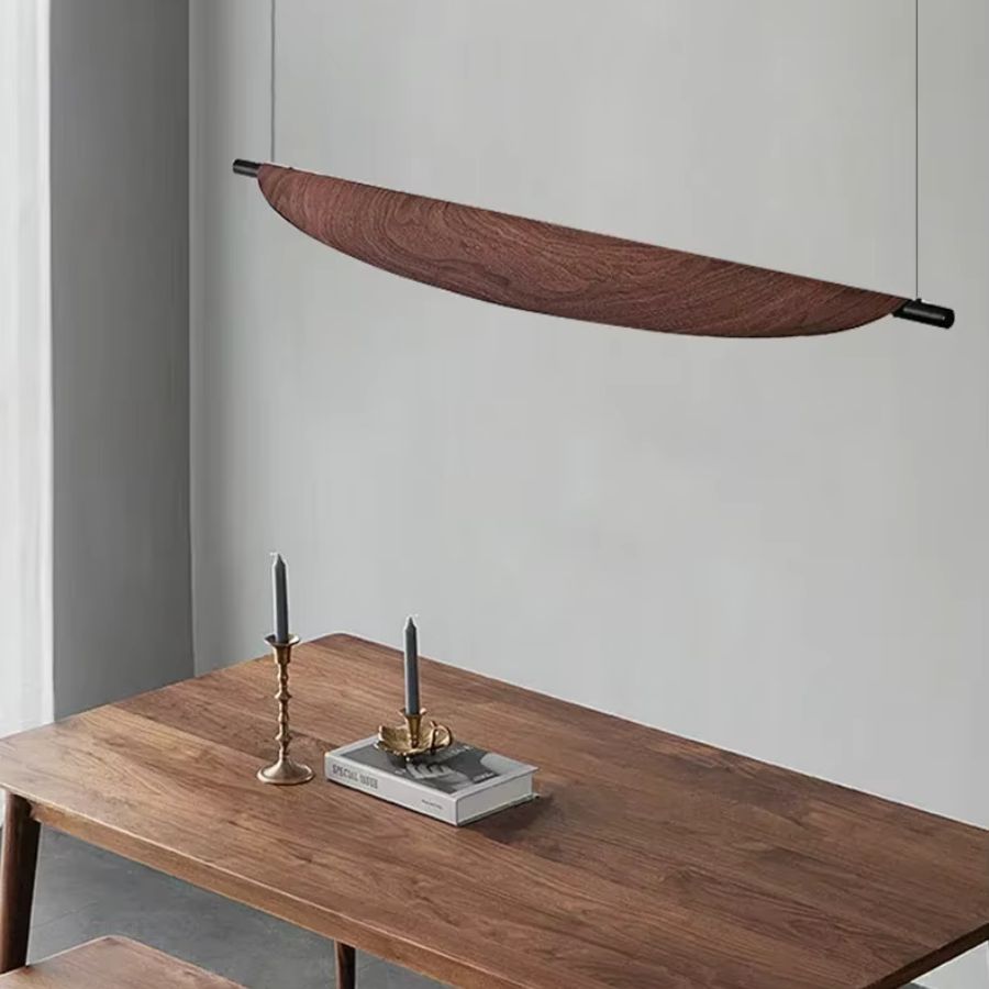 Suspendue au-dessus d’une table en bois, la lame courbe effet bois s’intègre dans un décor minimaliste et chaleureux