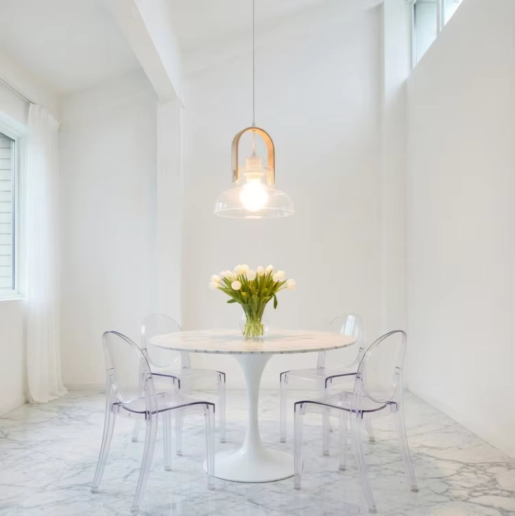 Une suspension en frêne naturel et verre soufflé transparent éclaire une salle à manger blanche au style minimaliste