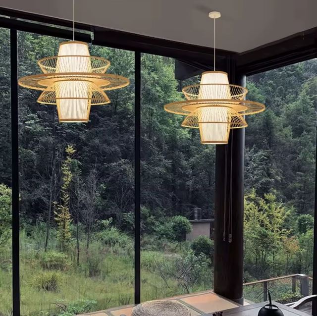 Duo de suspensions lanterne japonaise dans un intérieur avec baies vitrées ouvertes sur une vue panoramique de forêt.
