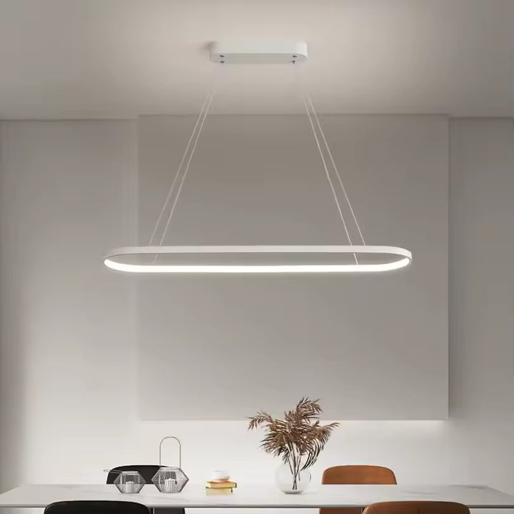 Suspendu au-dessus d’une table, ce lustre LED blanc aux lignes arrondies souligne un décor minimaliste