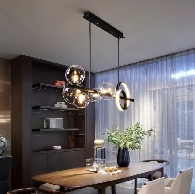Suspension design avec globes en verre transparent et anneaux LED, illuminant une salle à manger moderne aux meubles en bois et à l’ambiance chaleureuse et élégante.