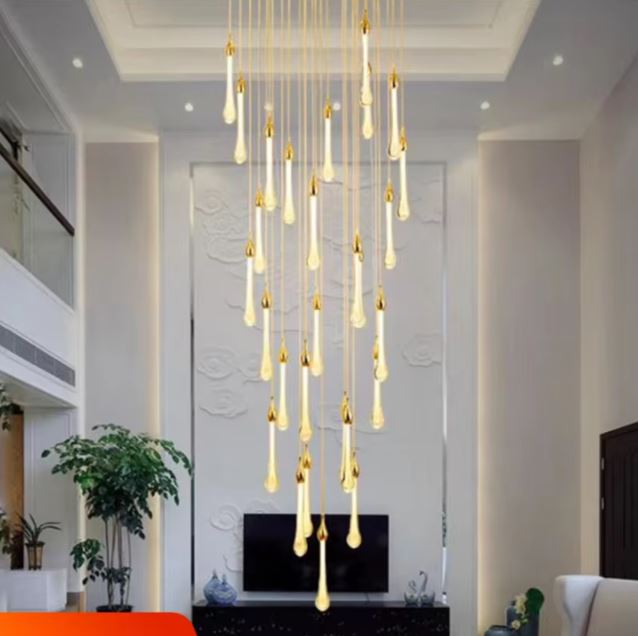 Suspension gouttes LED dorées installée dans un salon élégant avec plafond très haut et mur sculpté en relief derrière la télé.