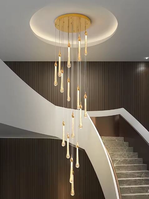 Suspension goutte LED dorée installée dans une cage d’escalier arrondie avec murs boisés et plafond encastré circulaire.