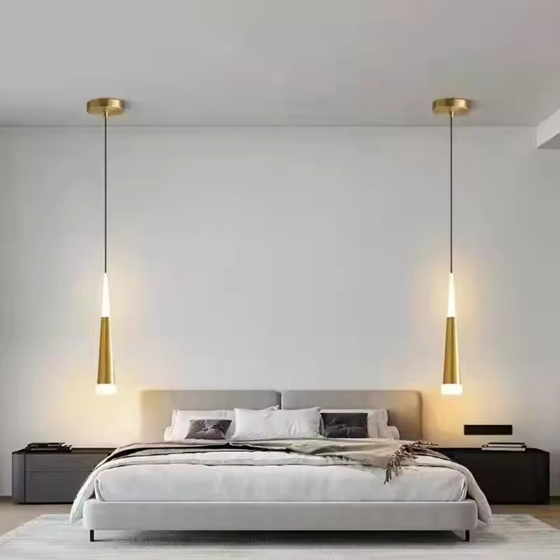 Ambiance épurée avec deux suspensions LED effilées dorées encadrant le lit dans une chambre contemporaine
