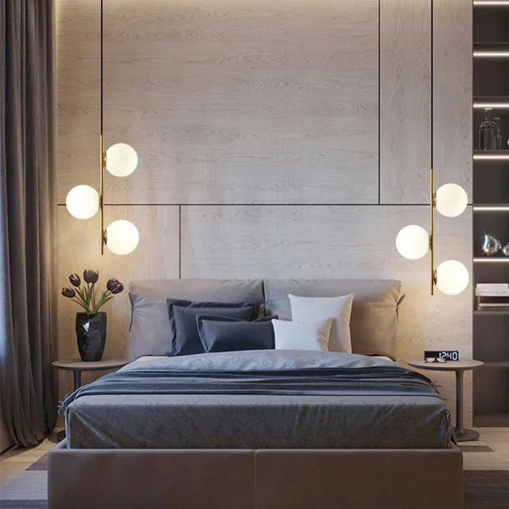 Suspension LED multi-sphères installée de part et d'autre d'un lit dans une chambre design moderne.
