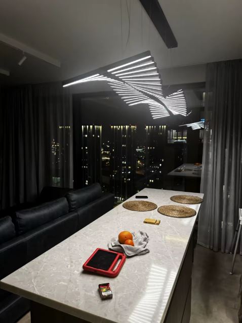 Suspension LED noire au style futuriste et linéaire, luminaire ondulé idéal pour un îlot contemporain.