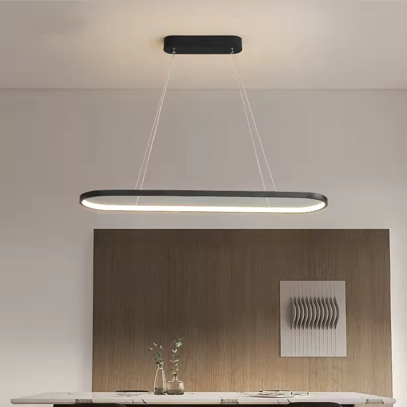 Un anneau LED noir aux angles arrondis structure l’éclairage d’une salle à manger moderne et épurée