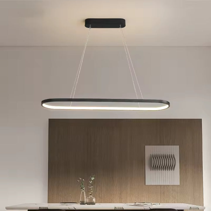Un anneau LED noir aux angles arrondis structure l’éclairage d’une salle à manger moderne et épurée