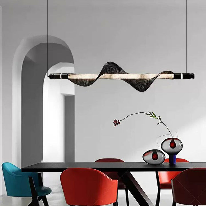 Suspension LED à ondulation moderne illuminant une grande table de salle à manger.
