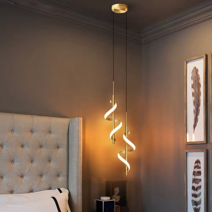Deux suspensions LED dorées à ruban hélicoïdal diffusent une lumière chaude de chaque côté d'un lit, au design contemporain.