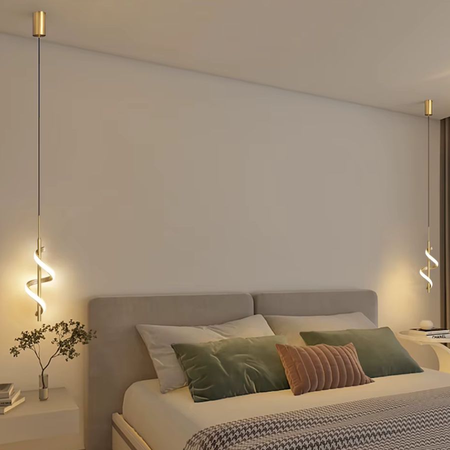 De chaque côté d'un lit, deux suspensions LED dorées en spirale lumineuse créent une ambiance douce et contemporaine.