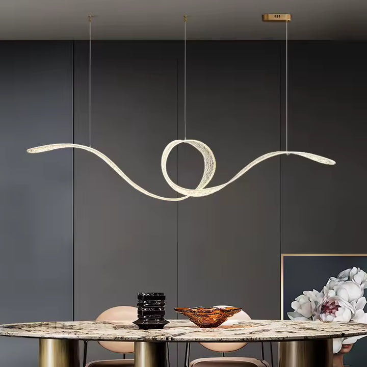 Suspendue au-dessus d'une table en marbre, une suspension LED sculpturale à boucle centrale au design fluide et organique.