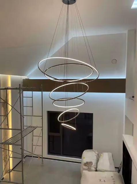 Suspension LED contemporaine en spirale lumineuse, en cours d'installation dans un salon moderne avec grande hauteur sous plafond.