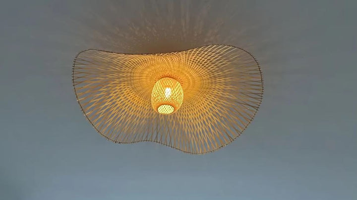 Détail de suspension libellule en bambou tressé, luminaire bohème naturel aux motifs ajourés et à la lumière chaleureuse.