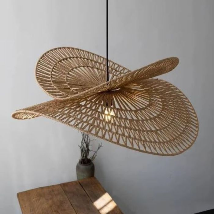 Suspension libellule en rotin naturel avec un design élégant, éclairant une table en bois pour une ambiance chaleureuse.