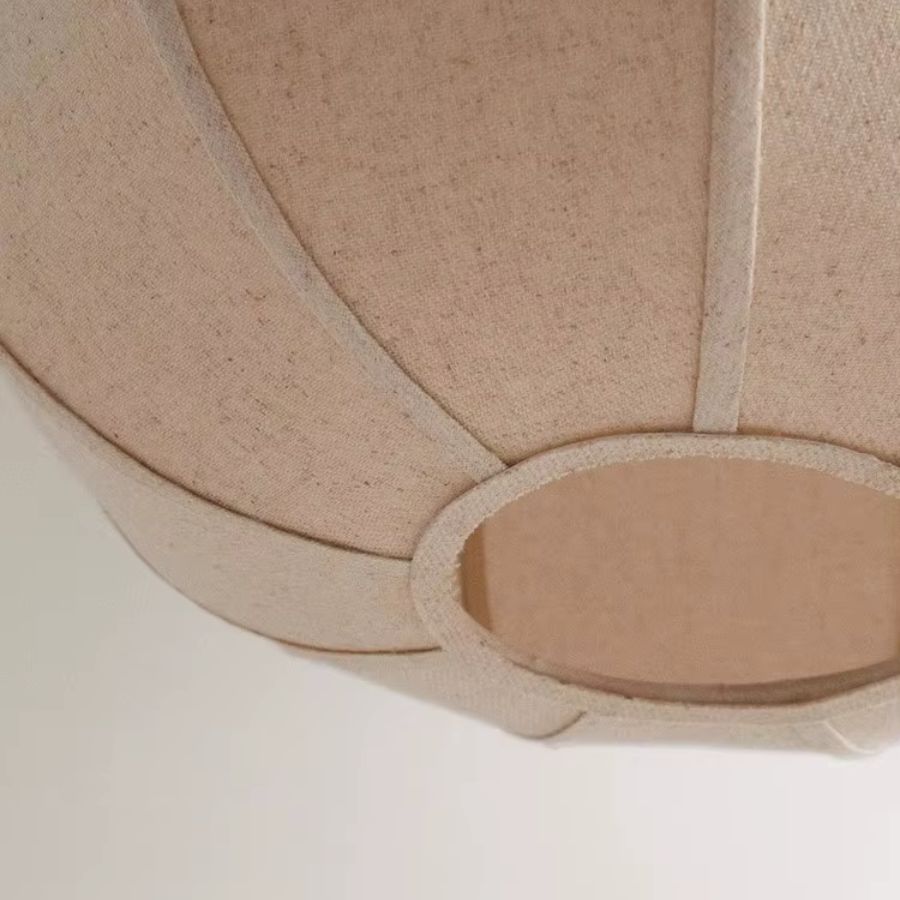 Vue rapprochée d’une suspension en lin beige montrant l’abat-jour à pétales galbés et sa texture naturelle
