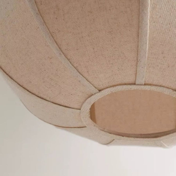 Vue rapprochée d’une suspension en lin beige montrant l’abat-jour à pétales galbés et sa texture naturelle