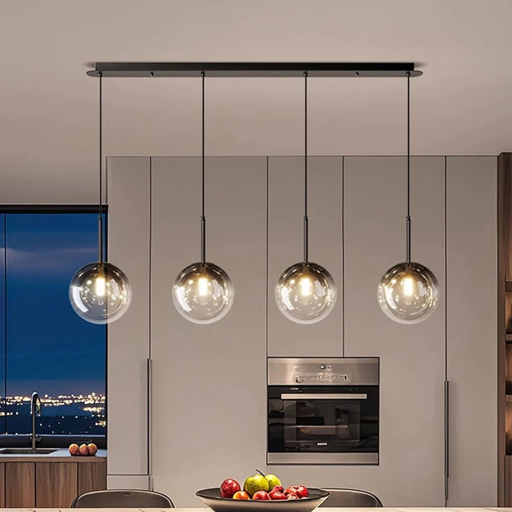 Suspension linéaire design en barre à globes de verre mise en valeur dans une cuisine ouverte moderne.