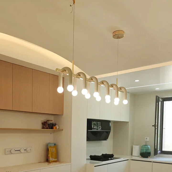 Suspension linéaire contemporaine à arches et doubles globes installée au plafond d'une cuisine ouverte moderne.