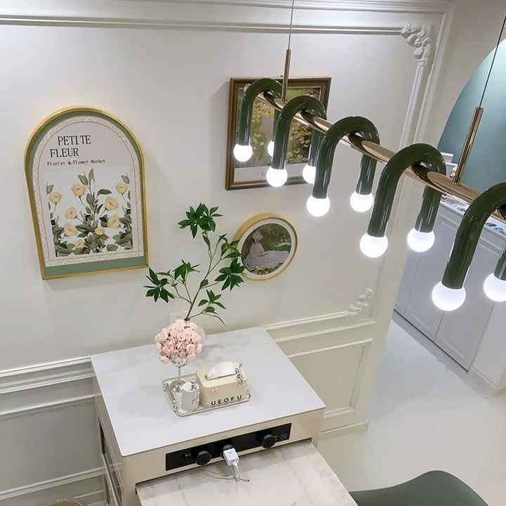 Vue en plongée sur l'espace repas illuminé par la suspension linéaire à arches et globes raffinés.