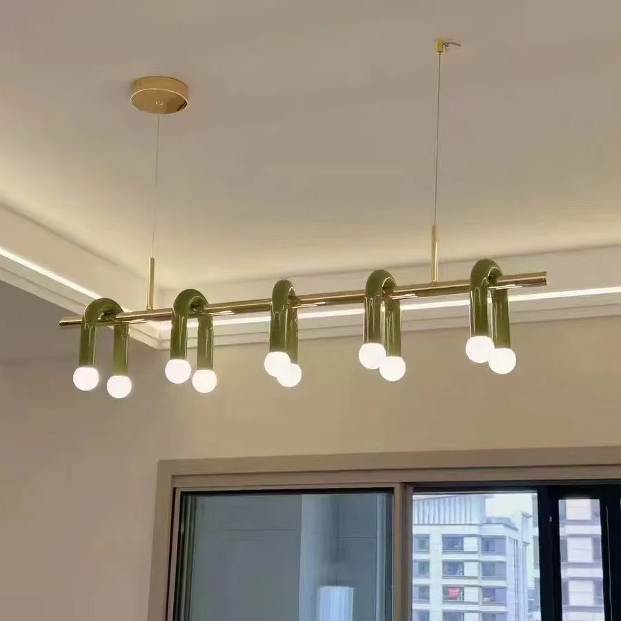 Suspension linéaire verte et dorée à arches et globes lumineux installée au plafond d'un salon moderne