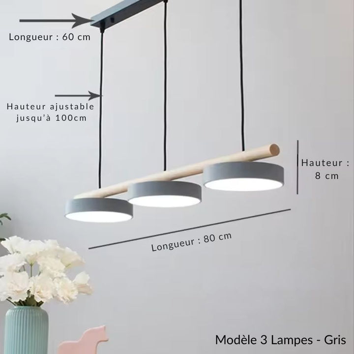 Sobre et linéaire, la suspension associe trois disques gris à une barre en bois clair d’inspiration scandinave