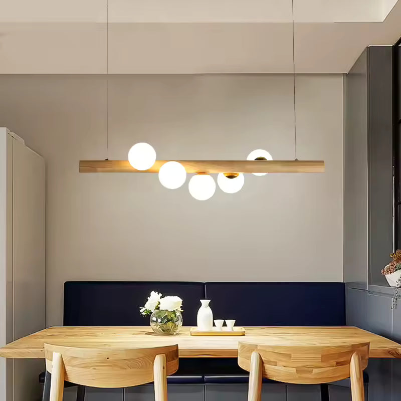 Au-dessus d’un coin repas en bois clair, cette suspension à globes lumineux adopte un style japandi doux et minimaliste.