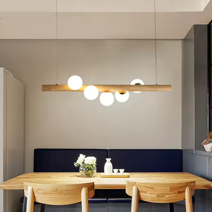 Au-dessus d’un coin repas en bois clair, cette suspension à globes lumineux adopte un style japandi doux et minimaliste.