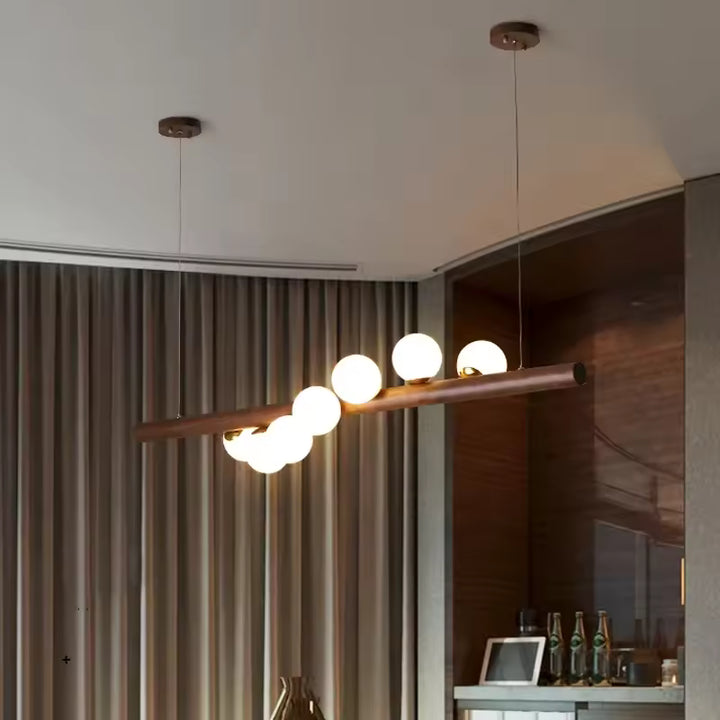 Vue en perspective d’une suspension linéaire en bois à globes lumineux, au design contemporain, épuré et chaleureux.