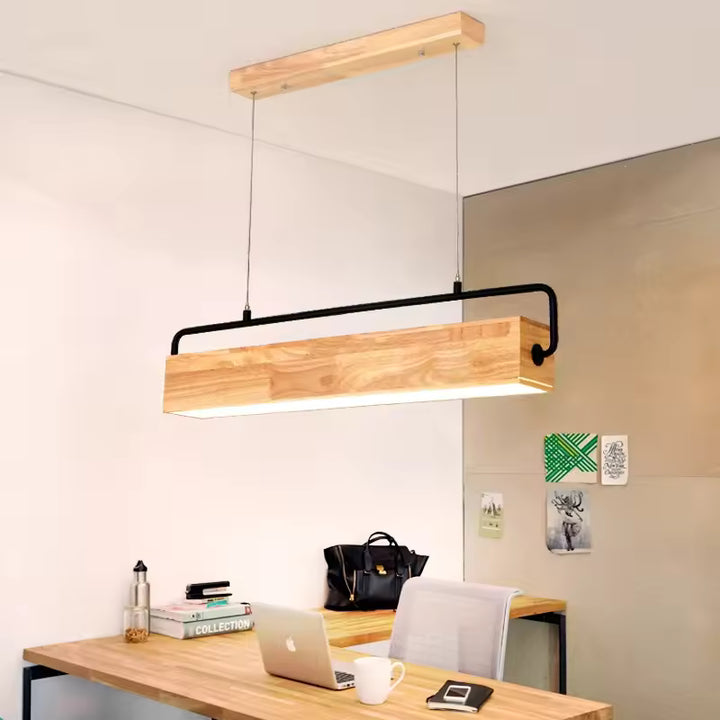 Au-dessus d'un bureau en bois, suspension linéaire en bois massif à armature métallique noire, de style industriel et moderne.