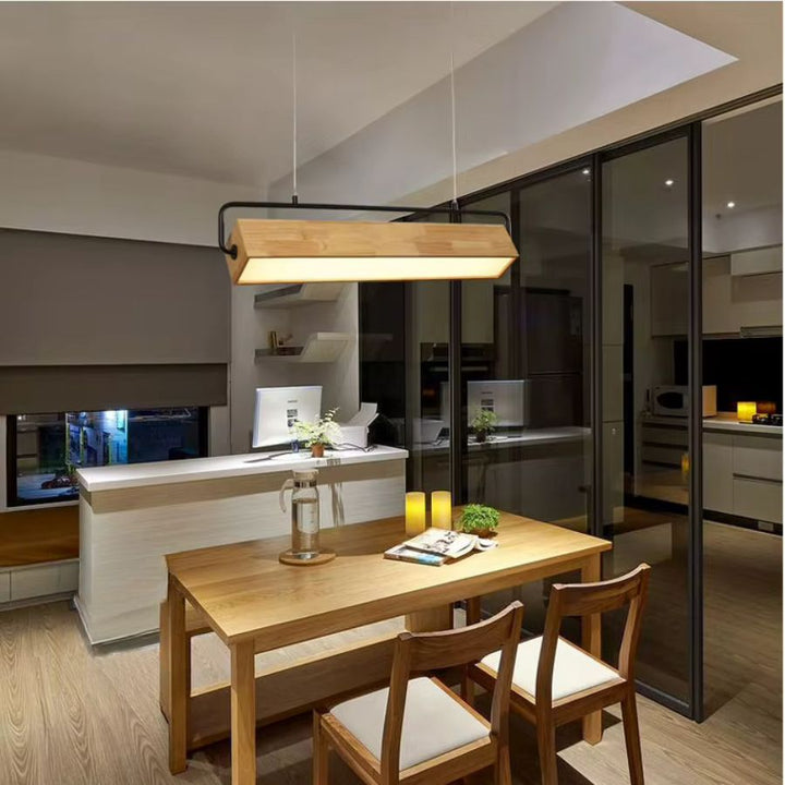 Au-dessus d'une table en bois, suspension linéaire en bois massif et métal noir, dans une salle à manger moderne et chaleureuse.