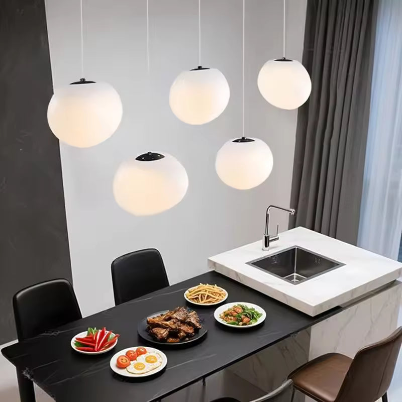 Suspension design contemporaine à globes opalins et spots orientables au-dessus d’un îlot de cuisine