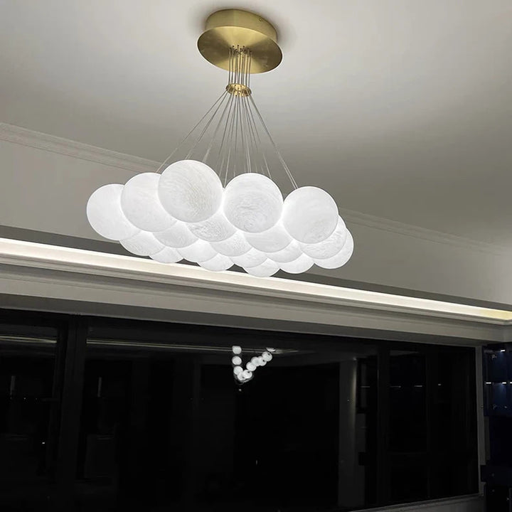 Suspension linéaire à globes en verre opalin blanc avec rosace en laiton brossé, idéale au-dessus d'une table à manger.