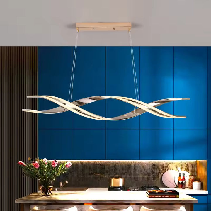 Dans une cuisine aux façades bleues, suspension LED doré rose à rubans entrelacés, au design ondulant et contemporain.